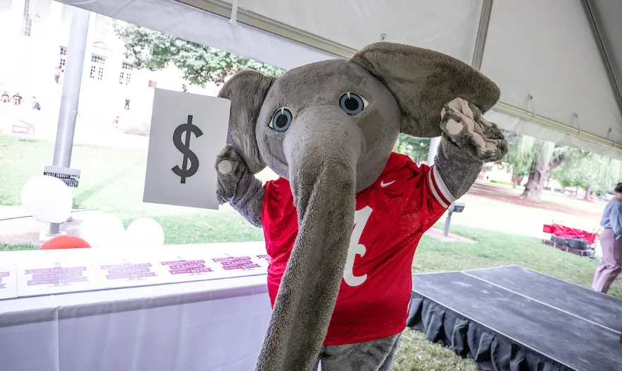 Big Al holding a dollar sign sign
